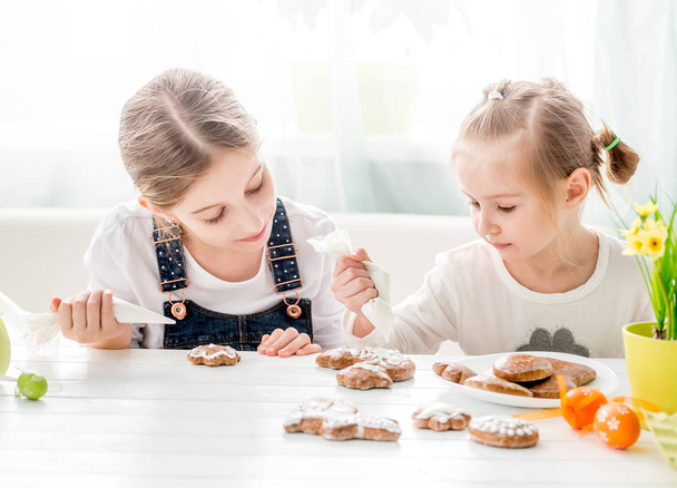 Child girl decorating Easter cookies - 写真・画像
