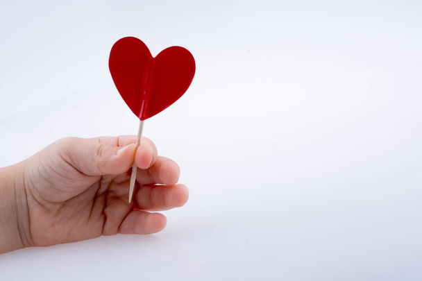 Forma de corazón de color rojo en la parte superior de un palo en la mano
 - Foto, Imagen