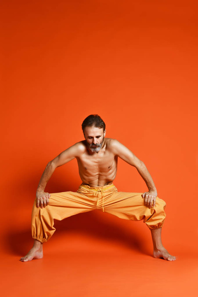 Portrait of yogi men doing yoga exercise on black mat, he breath and performing Upward abdominal lock, Uddiyana Bandha. - Photo, image