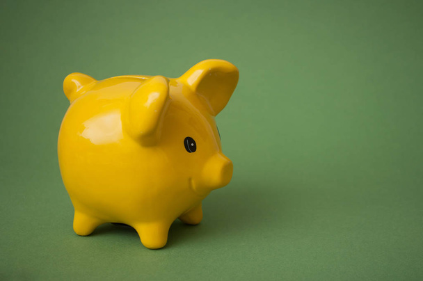 closeup of yellow piggy bank on green background  - Foto, afbeelding