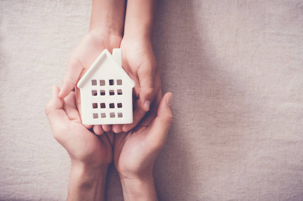 Adult and child hands holding toy house, family home and homeless shelter concept - Foto, imagen