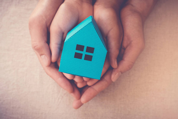 Adult and child hands holding toy house, family home and homeless shelter concept - Photo, image