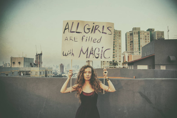 Дівчинка стоїть на даху з плакат «всі дівчата наповнені магії» концепція Міжнародний жіночий день - Фото, зображення