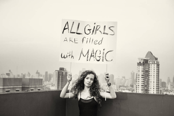 La fille se tient sur le toit avec une affiche "Toutes les filles sont remplies de magie" concept de la Journée internationale de la femme
 - Photo, image