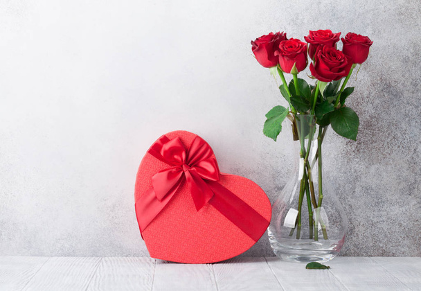 Открытка на день Святого Валентина с букетом из красных розовых цветов и подарочной коробкой. С пространством для поздравлений
 - Фото, изображение