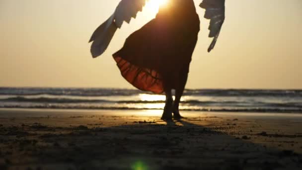 Silhouette of beautiful female angel walking barefoot toward the sea at sunset. - Footage, Video