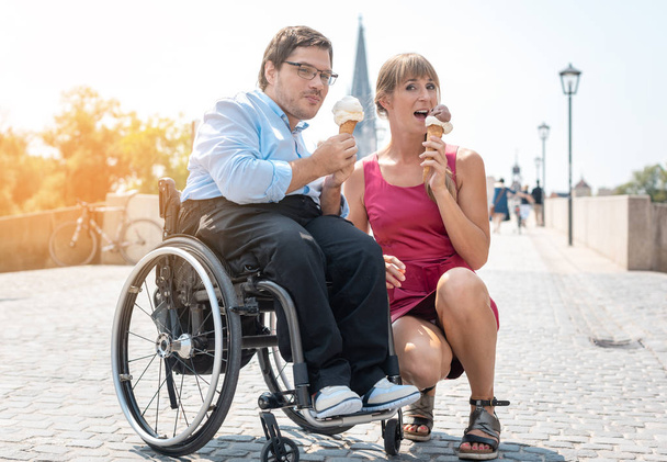 Hombre discapacitado y su amigo comiendo helado en la ciudad
 - Foto, Imagen
