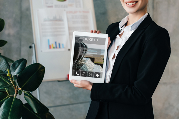 vista recortada de mujer de negocios sonriente sosteniendo tableta digital con entradas en la pantalla
  - Foto, imagen