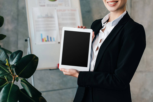 partial view of smiling businesswoman holding digital tablet with black screen - Foto, afbeelding