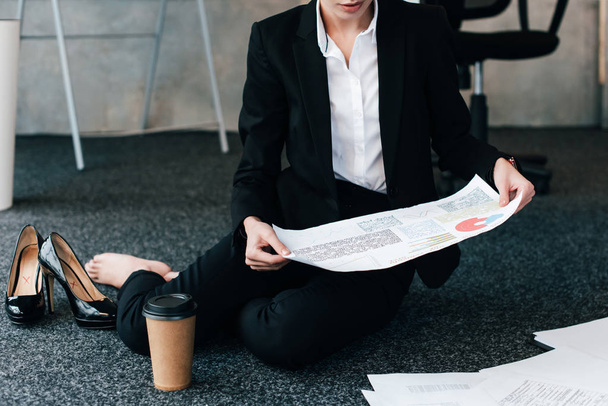 cropped view of businesswoman sitting on floor and reading document - Photo, Image