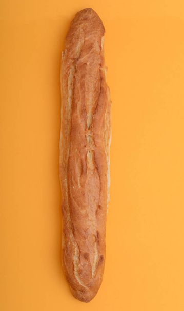 Tasty rustic baguette on the orange background. Top view - Photo, image