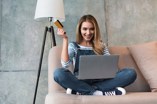 happy beautiful woman with laptop smiling and holding credit card in hand - Foto, Imagen