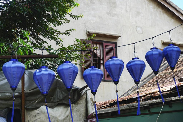 Vintage blauwe zijde lantaarns opknoping boven een straat in de oude Hoi An, Vietnam. De lantaarns zijn een traditionele ambacht uit het gebied. - Foto, afbeelding