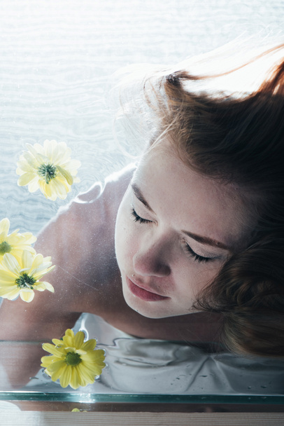 cropped view of beautiful woman posing underwater with yellow flowers - Zdjęcie, obraz