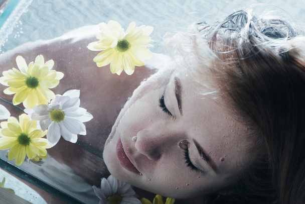 close up of beautiful girl posing underwater with chamomiles - Фото, зображення