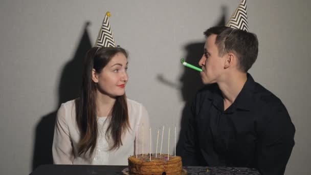 Smiling couple celebrates a holiday playing with party blowers - Filmmaterial, Video