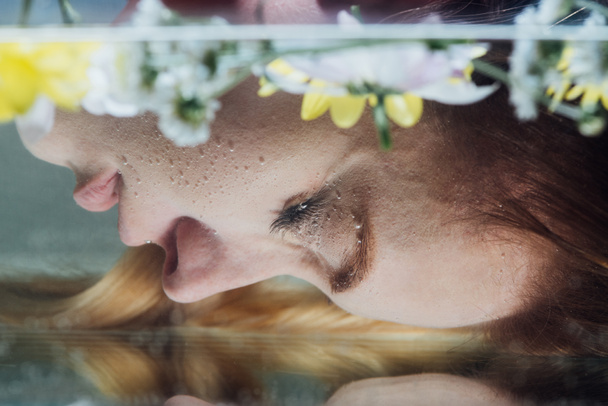 close up of young woman posing over water with flowers - Foto, imagen