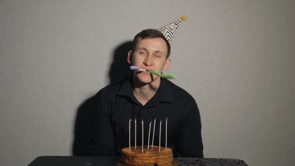 Close up van een jonge man met chocolade cake en een kaarsen spelen met partij ventilatoren. - Video