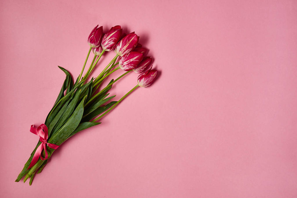 Bouquet of tulips on pink pastel background, copy space. Spring minimal concept. Womens Day, Mothers Day, Valentine's Day, Easter, birthday. Nature background. Flat lay, top view - 写真・画像