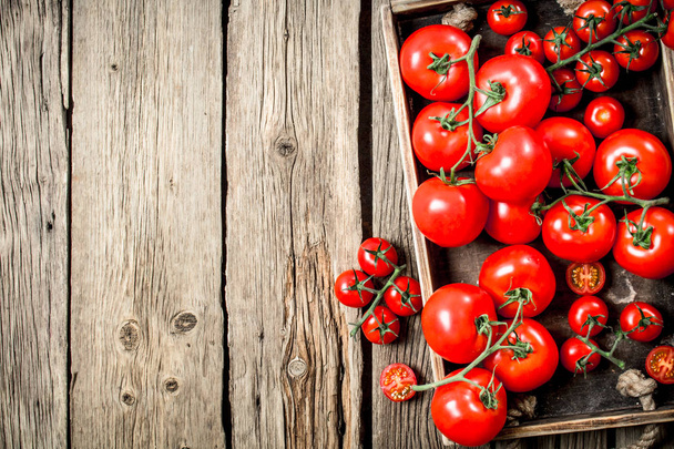 Fresh tomatoes in a wooden tray. On a wooden background. - Φωτογραφία, εικόνα