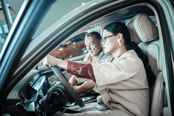 Woman with long dark hair sitting behind the wheel of her new car - Φωτογραφία, εικόνα