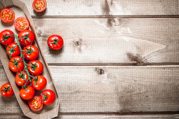 Fresh cherry tomatoes in the tray. On a wooden background. - Fotografie, Obrázek