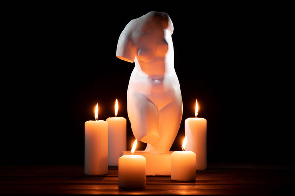 Bust of Venus and burning candles on a black background - Photo, Image
