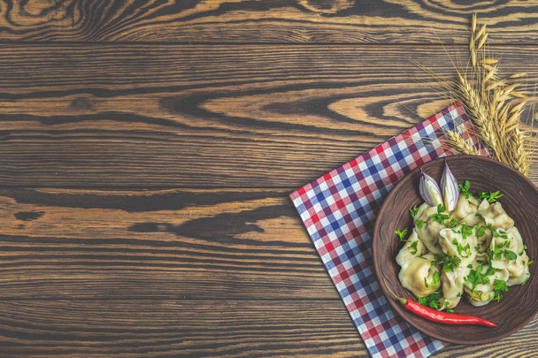 おいしい自家製肉餃子や新鮮なパセリのコピー スペース ダークウッドの木製テーブル面上皿にラビオリの伝統的なイタリアを上から表示します。. - 写真・画像