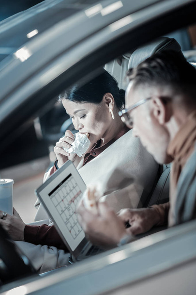 Ylikuormitetut liikemiehet työskentelevät ja syövät autossaan
 - Valokuva, kuva