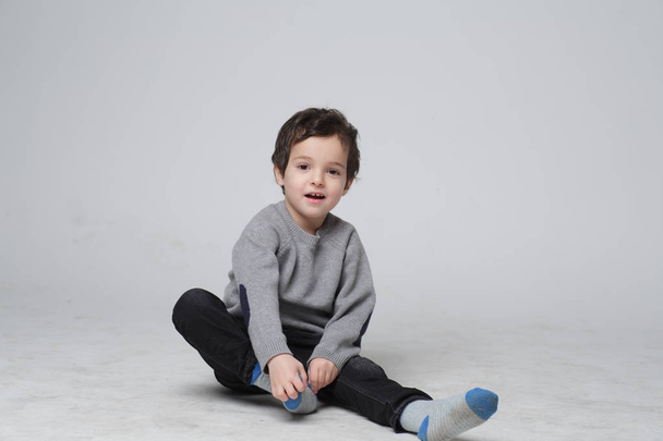 Retrato de niño lindo sentado aprendiendo a ponerse los calcetines por él mismo, niño feliz tirando de sus calcetines a su pie, concepto de desarrollo infantil
 - Foto, Imagen