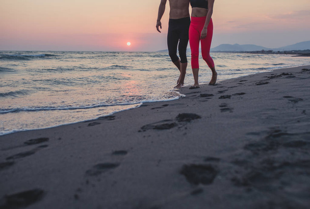 Unrecognisable sportsman and sportswoman walking on sandy beach. - Foto, immagini