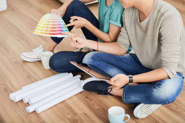 Crop Ansicht von Mann und Frau sitzen zusammen auf dem Boden mit Farbkarten und diskutieren neue Farben - Foto, Bild