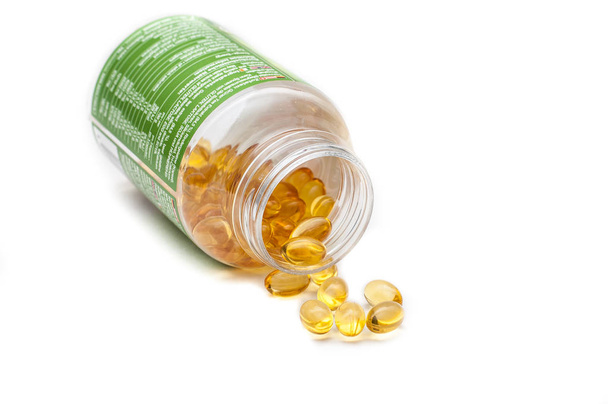 Omega 3 fish oil capsules spilled from a plastic bottle on a white background. Medical food supplements. Unsaturated fatty acid. Health care concept. - Photo, Image