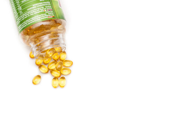 Omega 3 fish oil capsules spilled from a plastic bottle on a white background. Medical food supplements. Unsaturated fatty acid. Health care concept. - Foto, afbeelding