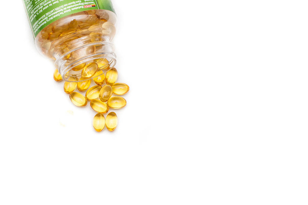 Omega 3 fish oil capsules spilled from a plastic bottle on a white background. Medical food supplements. Unsaturated fatty acid. Health care concept. - Fotó, kép