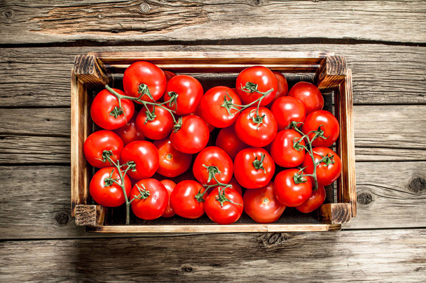 Ripe tomatoes in a wooden box. On a wooden table. - Foto, immagini