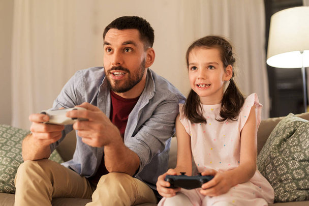 father and daughter playing video game at home - Фото, изображение