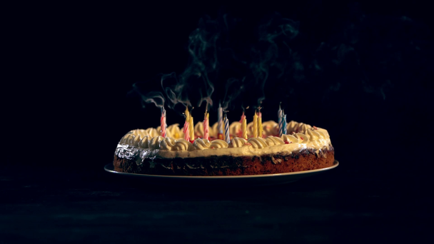studio shoot of burning candles blowing out on birthday cake on black background - Footage, Video