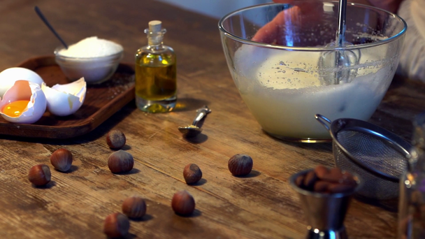 női szakács ostorozó tojás hab üvegtál, mixer, fából készült asztal  - Felvétel, videó
