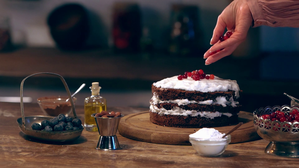 slow motion of female cook scattering redcurrant on creamy cake  - Materiaali, video