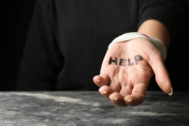 Woman with wrist bandage and word help written on her palm. Suicide awareness concept - Photo, Image