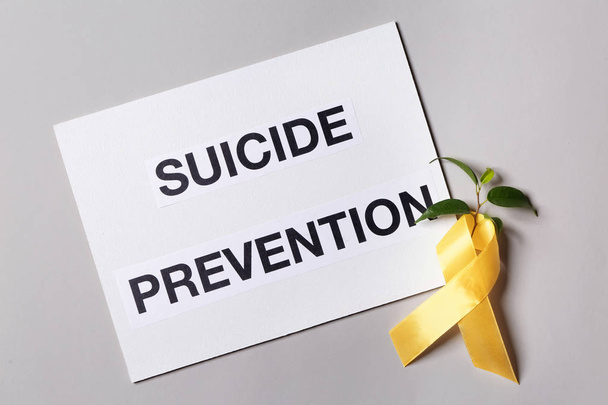 Arkusz papieru z tekstem zapobieganie samobójstwom i żółtą wstążkę na jasnym tle - Zdjęcie, obraz