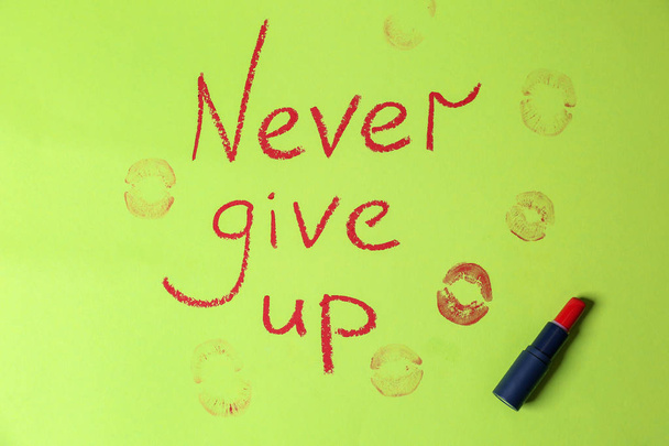 Text NEVER GIVE UP and lipstick marks on color background - Photo, Image
