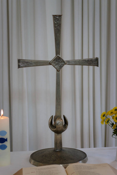 Pequeño altar con cruz santa, biblia abierta, vela de bautismo ardiente y flores en un jarrón
 - Foto, imagen