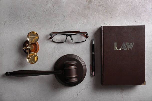 Tuomarin nuija, kirja, lasit ja oikeusasteikot harmaalla pohjalla
 - Valokuva, kuva