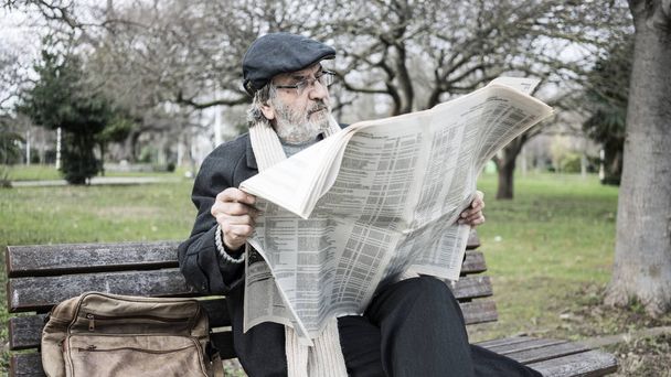 Old man reading newspaper in the park - Fotó, kép