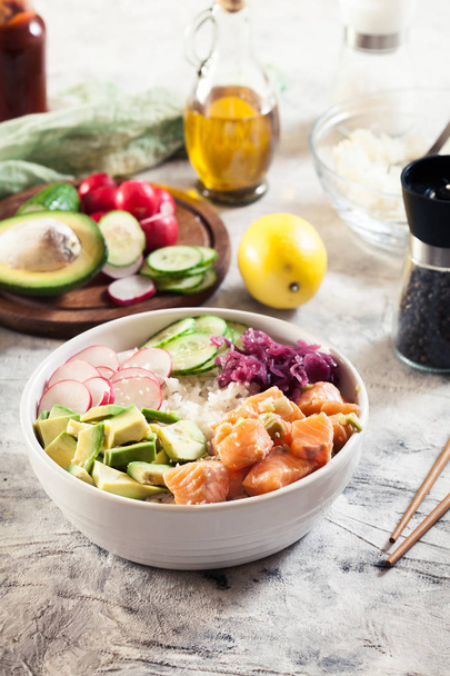 Poke bowl, traditional Hawaiian raw fish salad with rice, avocado, cucumber and radish on bright background - Foto, imagen