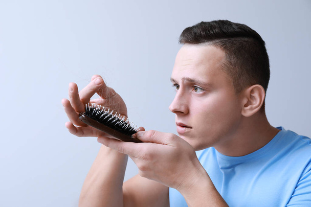 Людина з проблемою випадання волосся на сірому фоні
 - Фото, зображення