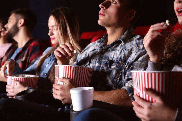 Amigos comiendo palomitas de maíz mientras ven películas en el cine
 - Foto, imagen