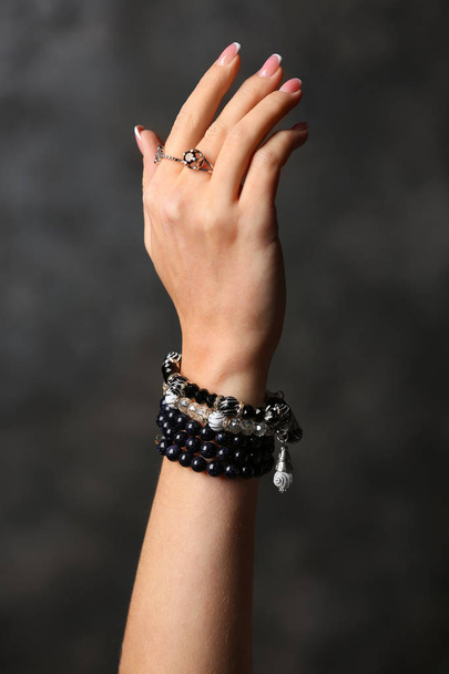 Main de jeune femme avec bijouterie élégante sur fond sombre
 - Photo, image